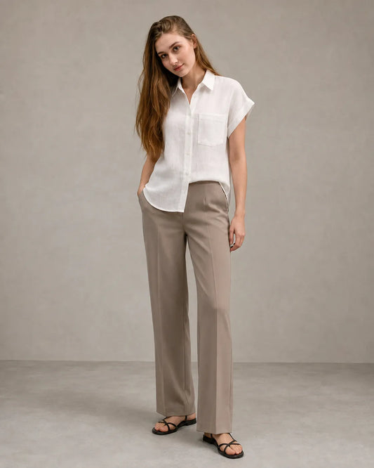 Woman wearing a well-pressed off-white linen shirt with a polo collar, styled with tailored trousers, illustrating properly cared-for linen clothing.