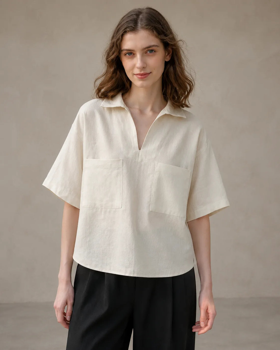 Woman wearing an oversized off-white linen V-neck shirt with short sleeves, front view.