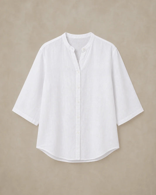 A loose-fit white 100% linen shirt with a V-neckline and curved hem, shown as a standalone product shot.