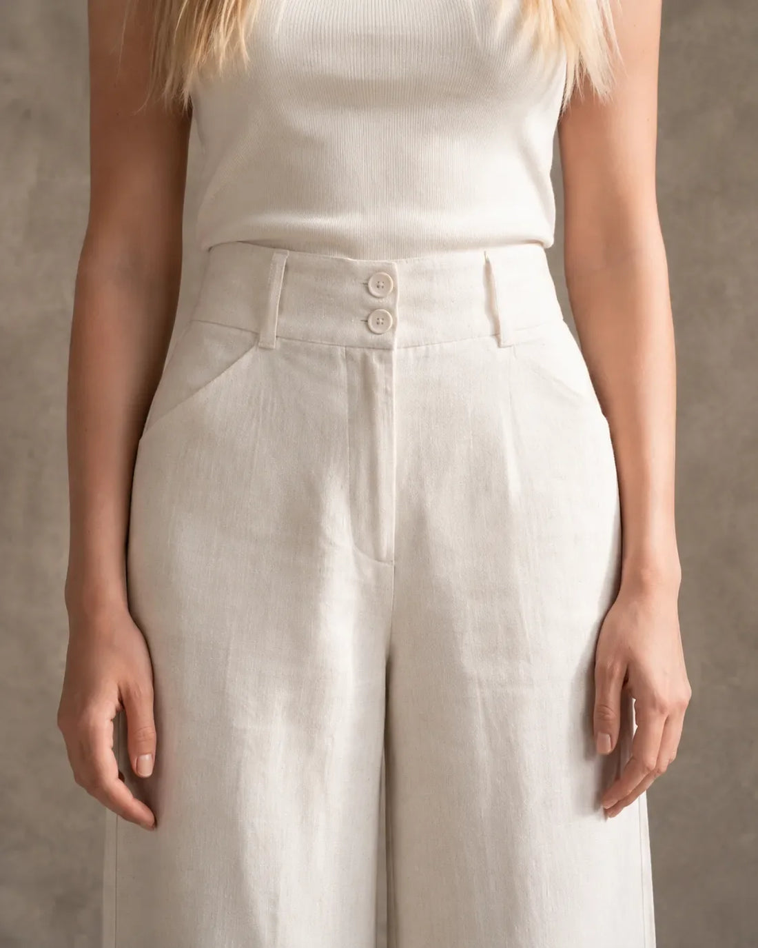 Close-up of the double-button waistband and slant pocket on hemp-coloured half-elastic wide-leg cotton-linen trousers.