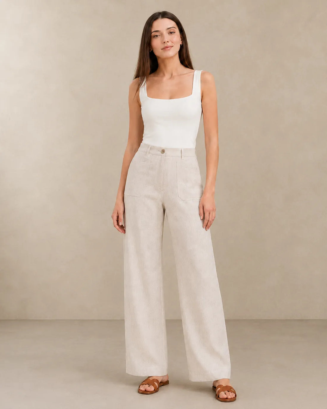 Close-up front view of natural linen wide-leg trousers with patch pockets, showing the fabric's natural texture.