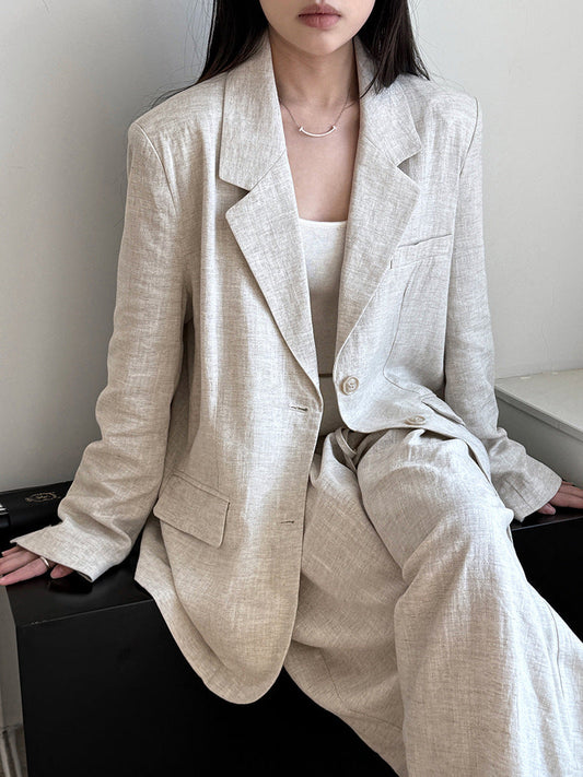 A model wears a tencel-linen blazer co-ord set in apricot, seated with the tailored blazer open over matching wide-leg trousers.