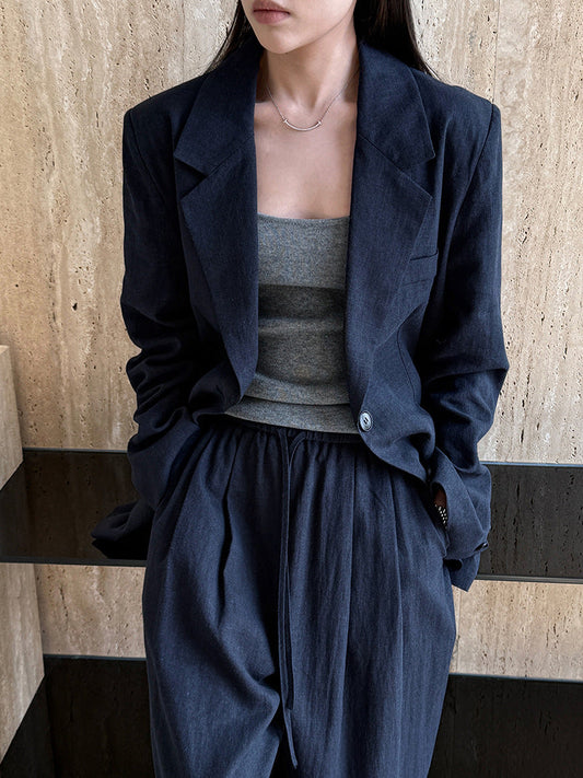 A woman wearing a navy tencel-linen blazer co-ord set, seated, representing Sarolu's approach to considered capsule wardrobe pieces.