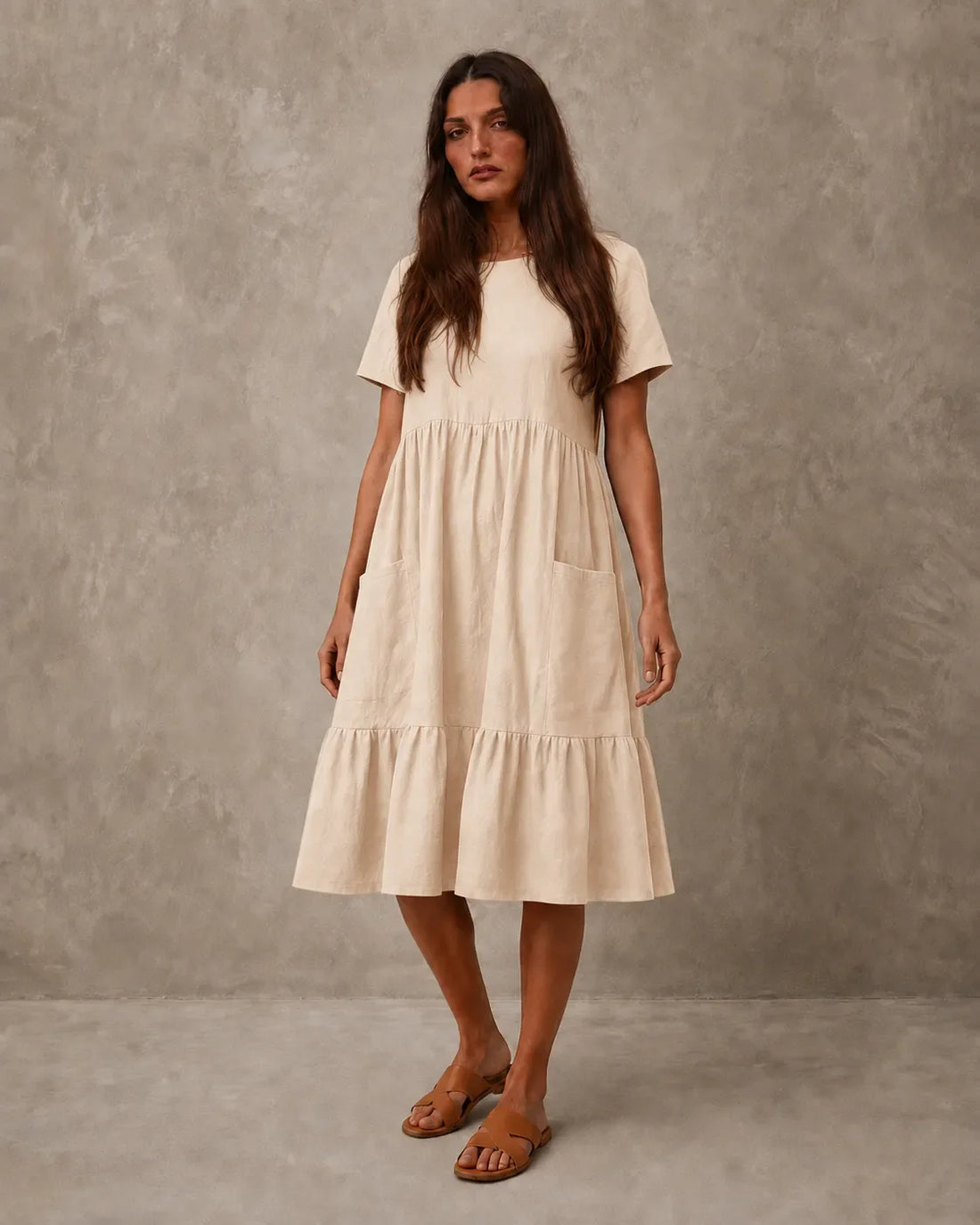Woman wearing an apricot cotton-linen loose-fit summer dress with short sleeves and a round neckline, shown from the front.