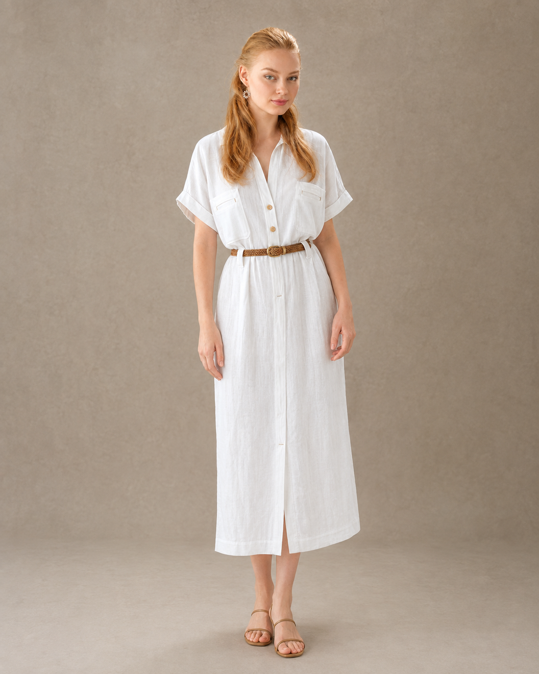 Woman wearing a flax-toned tencel-cotton A-line dress with a shirt collar and a braided brown leather belt, front view, a warm brown-adjacent alternative to a black dress.