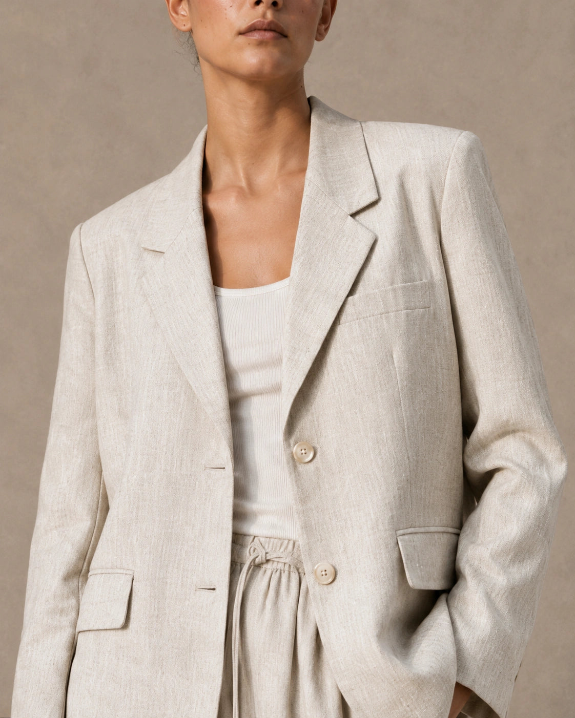 Close-up of the notched lapel, button closure and chest pocket on the apricot tencel-linen blazer.