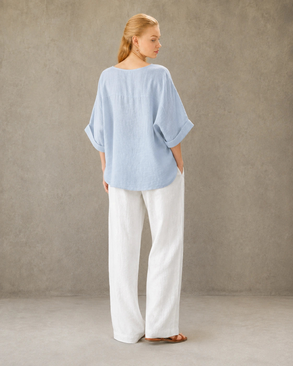 Driekwart achteraanzicht van een vrouw in een blauw bamboe-hennep blouse met ronde hals.
