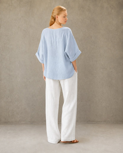 Driekwart achteraanzicht van een vrouw in een blauw bamboe-hennep blouse met ronde hals.