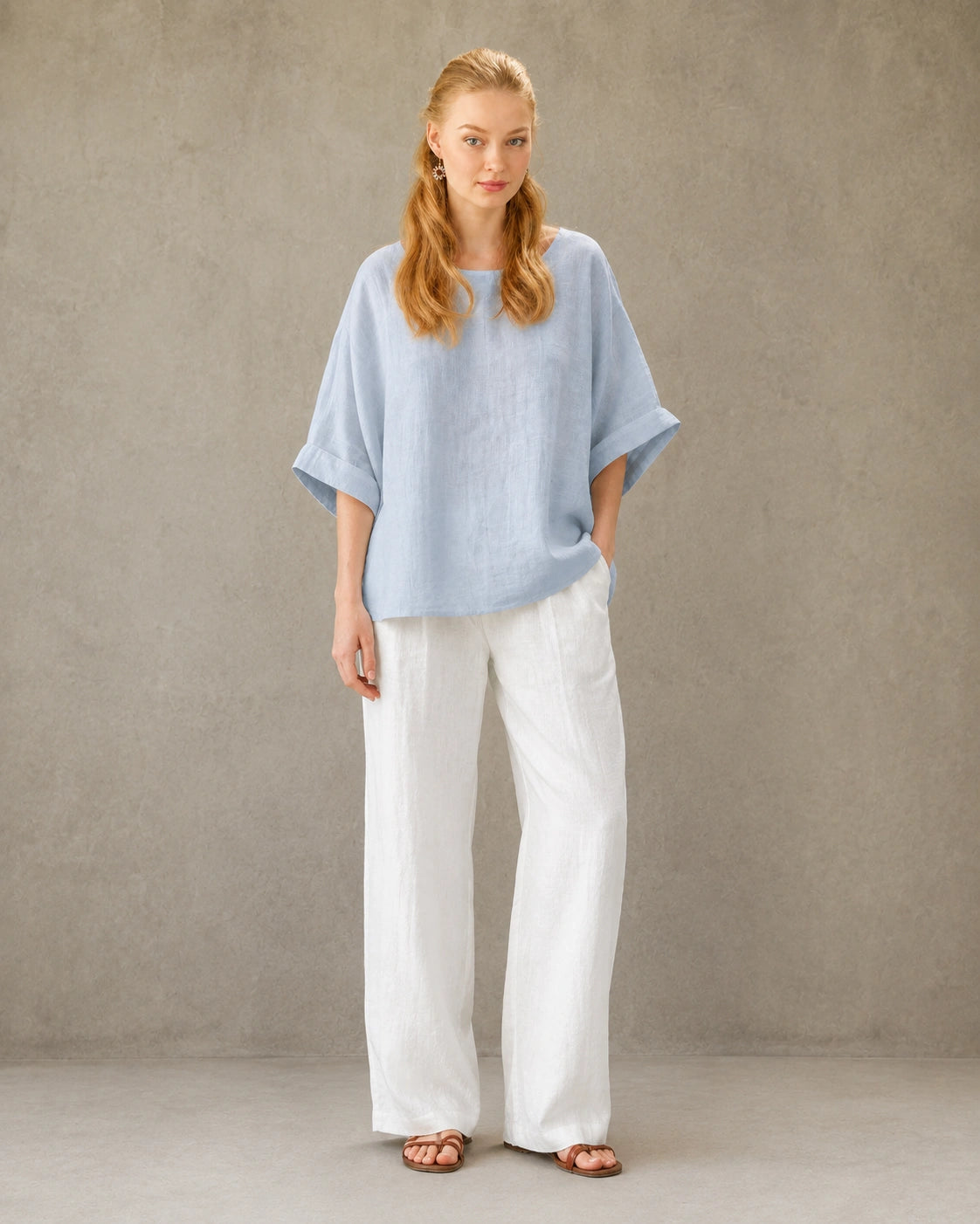 Volledige look van een vrouw in een blauw bamboe-hennep blouse met ronde hals, gecombineerd met een wijde witte broek.