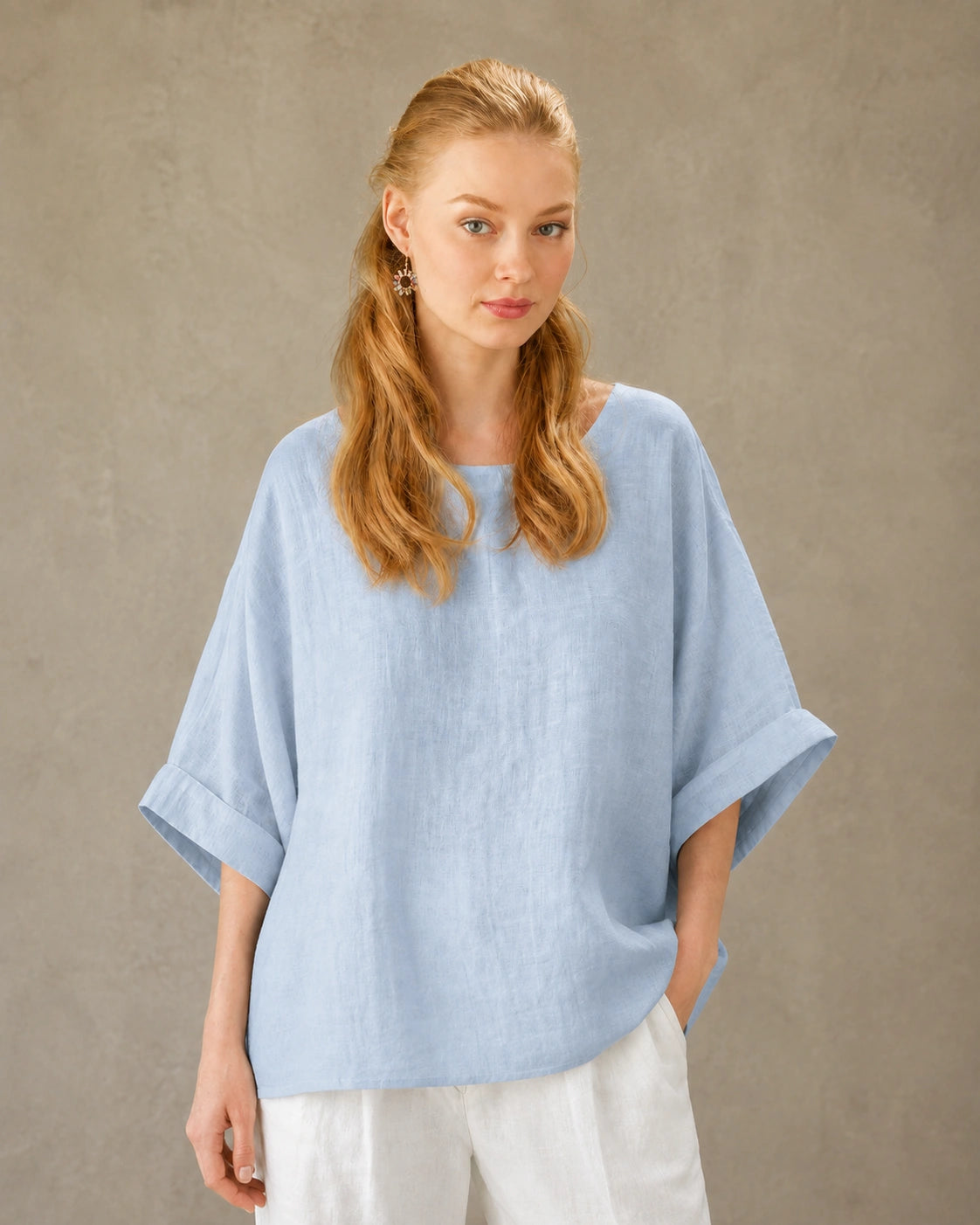 Vrouw draagt een blauw bamboe-hennep blouse met ronde hals, valschouder en driekwart mouwen, vooraanzicht.