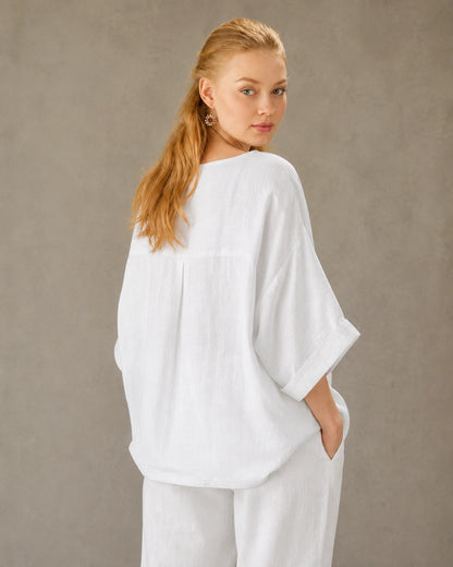 Driekwart achteraanzicht van een vrouw in een wit bamboe-hennep blouse met ronde hals.