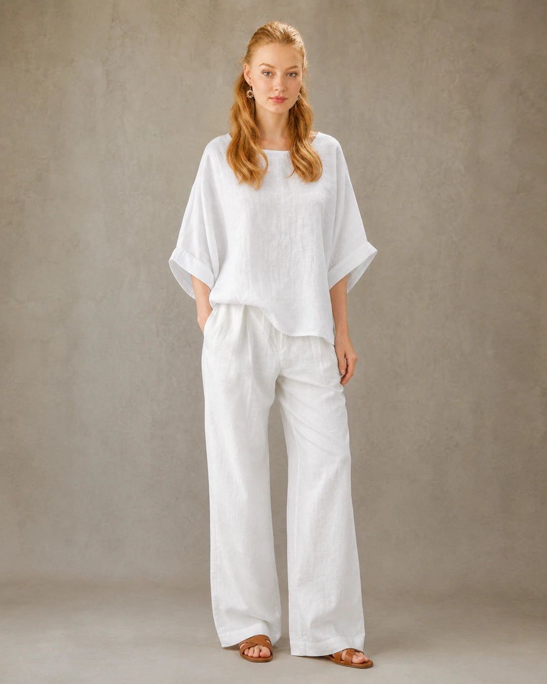 Volledige look van een vrouw in een wit bamboe-hennep blouse met ronde hals, gecombineerd met een wijde witte broek.