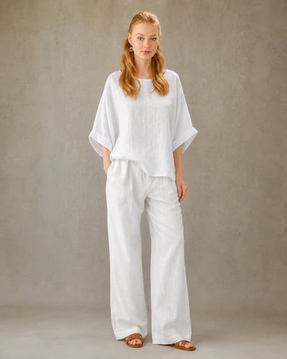 Volledige look van een vrouw in een wit bamboe-hennep blouse met ronde hals, gecombineerd met een wijde witte broek.