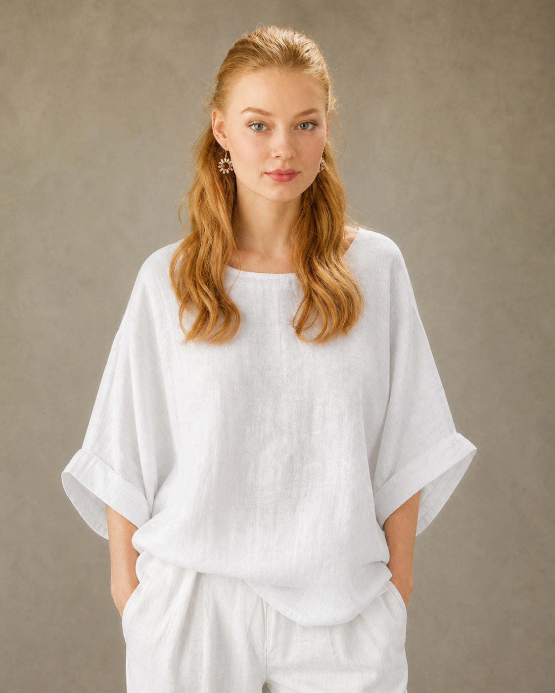 Vrouw draagt een wit bamboe-hennep blouse met ronde hals, valschouder en driekwart mouwen, vooraanzicht.