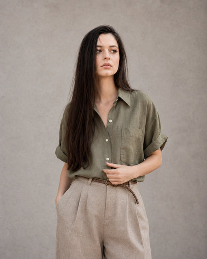 Vrouw draagt een groen katoen-linnen blouse met polokraag en korte mouwen, vooraanzicht.