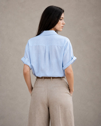 Achteraanzicht van een lichtblauw katoen-linnen blouse met korte, omgeslagen mouwen.