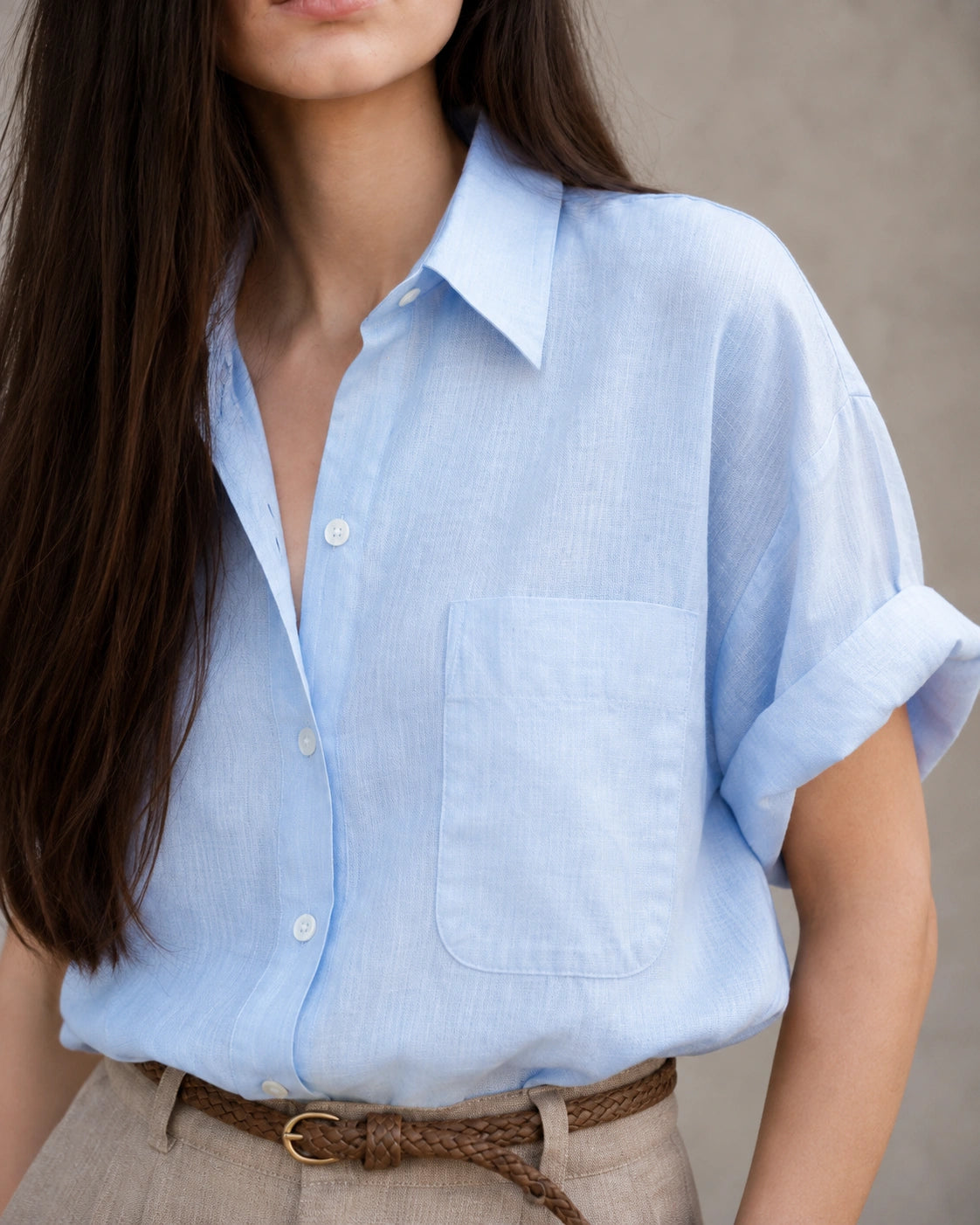 Close-up van de borstzak en knopenlijst van een lichtblauw katoen-linnen blouse.