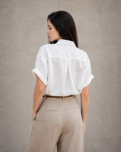 Achteraanzicht van een wit katoen-linnen blouse met korte, omgeslagen mouwen.