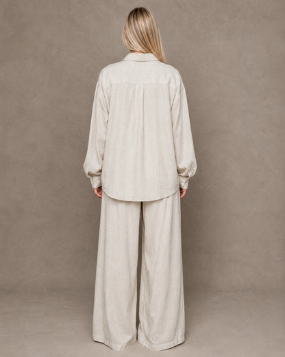 Back view of a beige linen shirt with a polo collar and long sleeves.