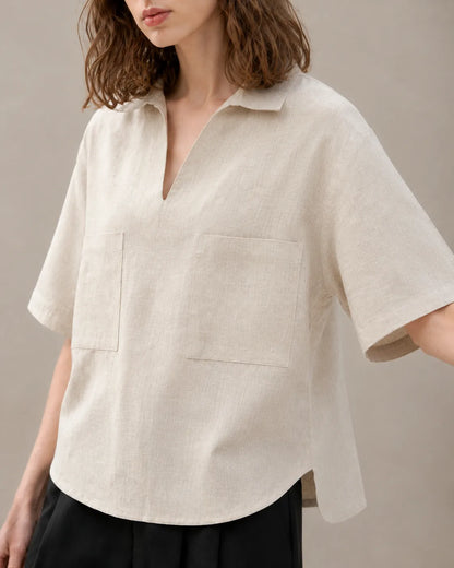 Close-up of the two patch pockets on an oversized linen beige V-neck shirt.