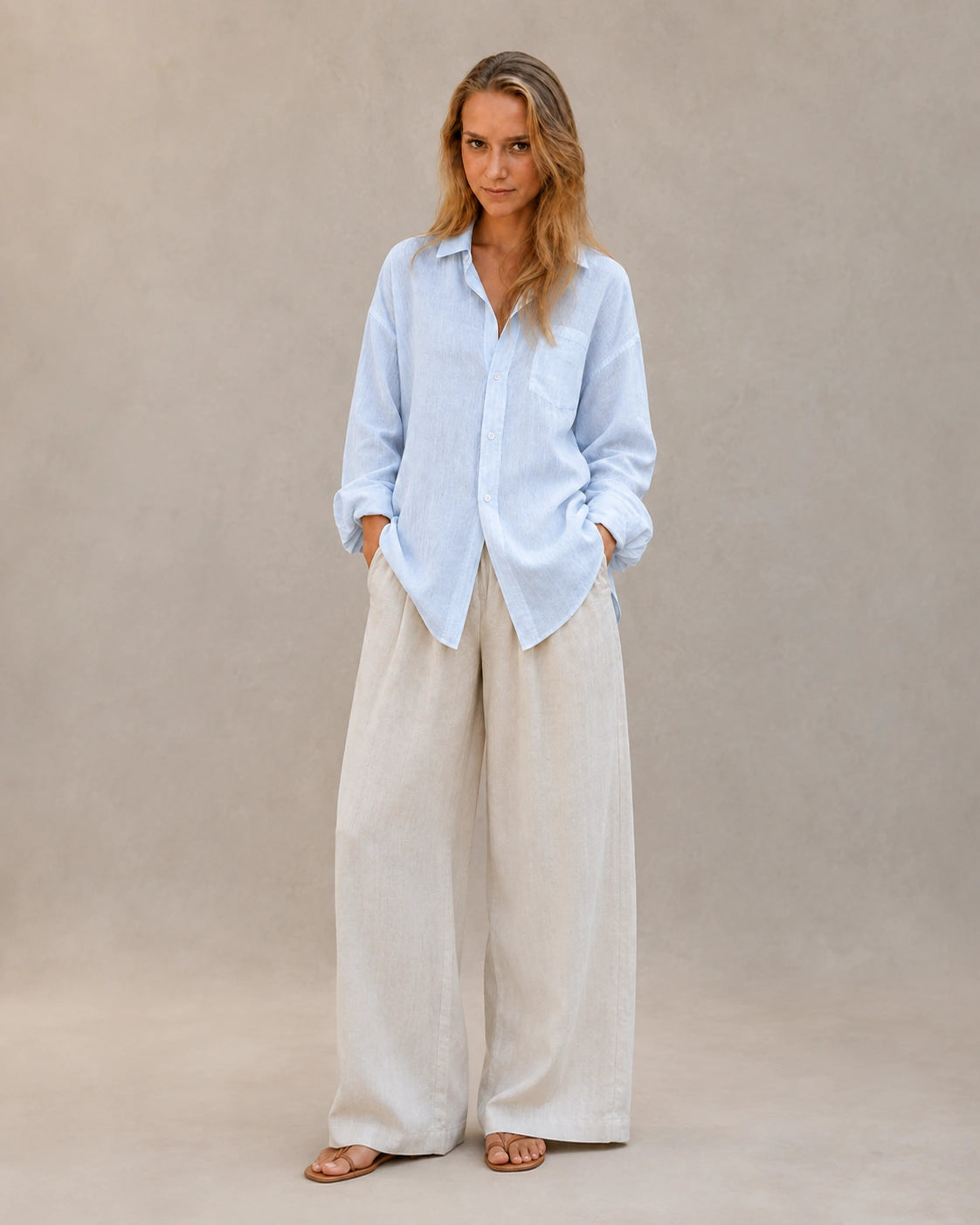 Volledige look van een vrouw in een oversized ijsblauw linnen blouse, gecombineerd met een wijde broek.