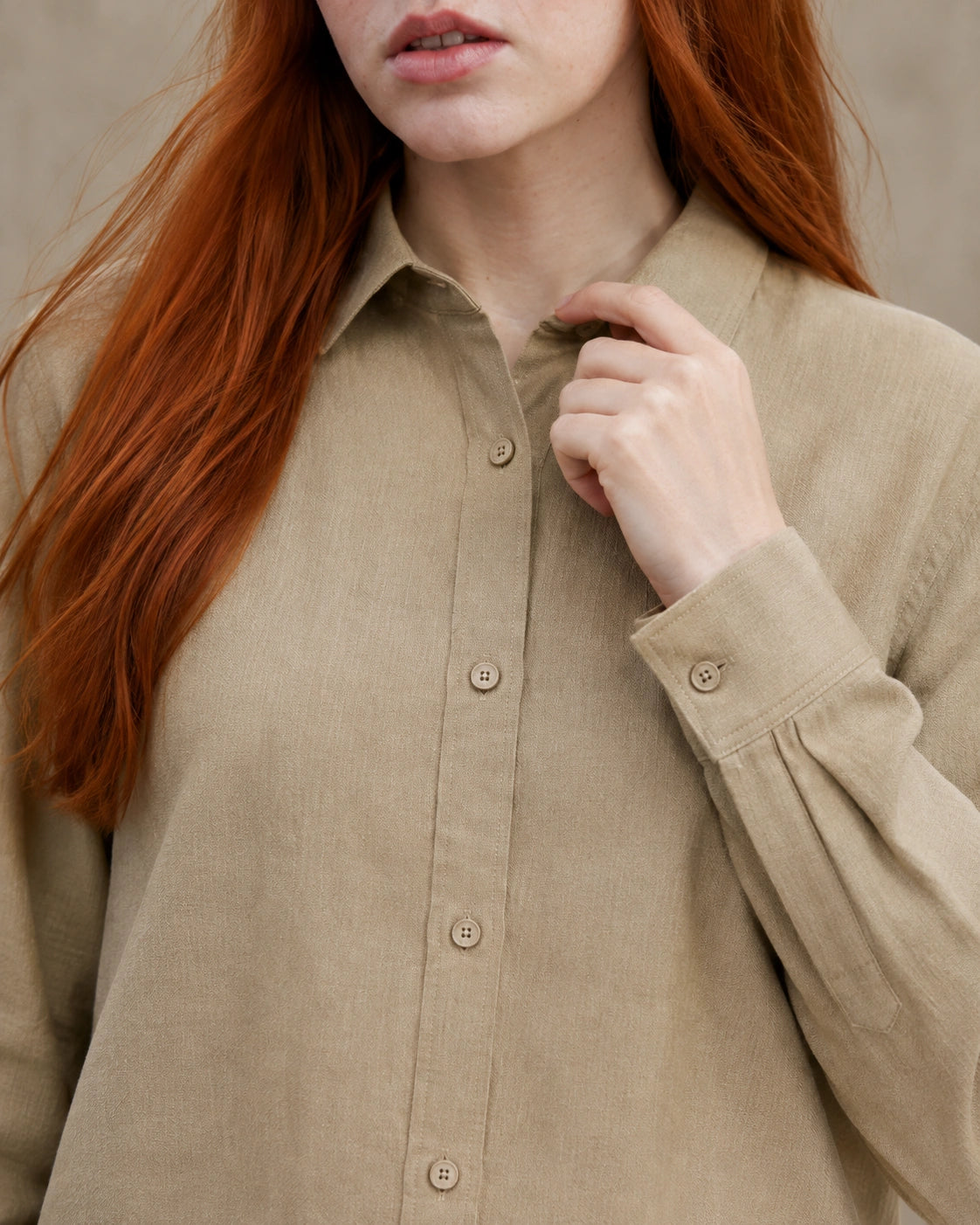 Close-up van de getailleerde kraag en knopenlijst van een kaki linnen blouse.