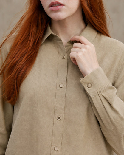 Close-up van de getailleerde kraag en knopenlijst van een kaki linnen blouse.