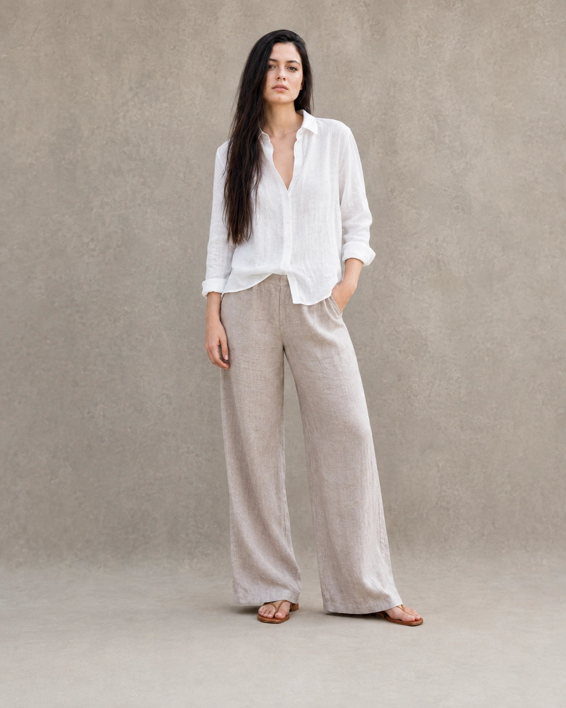 Volledige look van een vrouw in een losse wit linnen-katoenen blouse, gecombineerd met een wijde linnen broek.