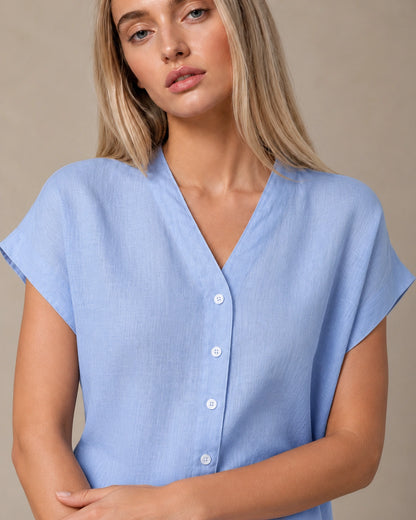 Close-up van de gedrapeerde, geplooide voorkant van een slank gesneden lichtblauw linnen blouse.