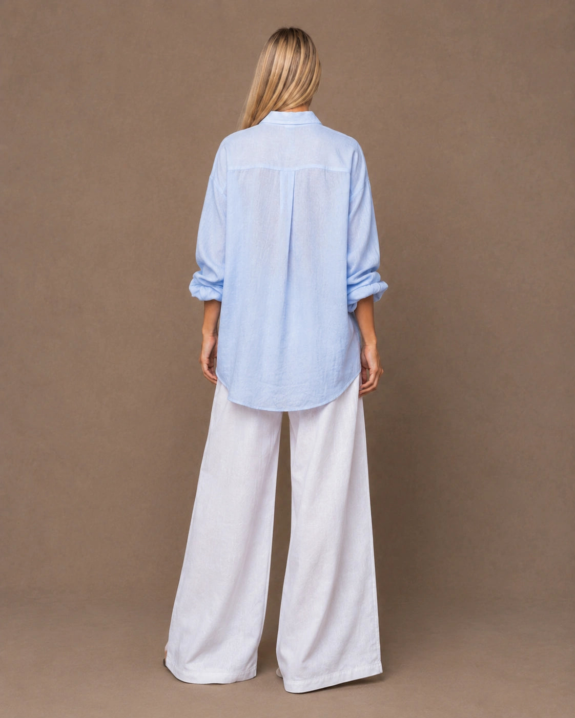 Achteraanzicht van een relaxte lichtblauw linnen blouse met lange mouwen.