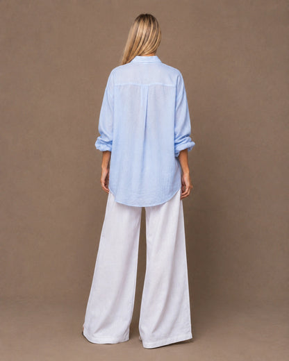 Achteraanzicht van een relaxte lichtblauw linnen blouse met lange mouwen.