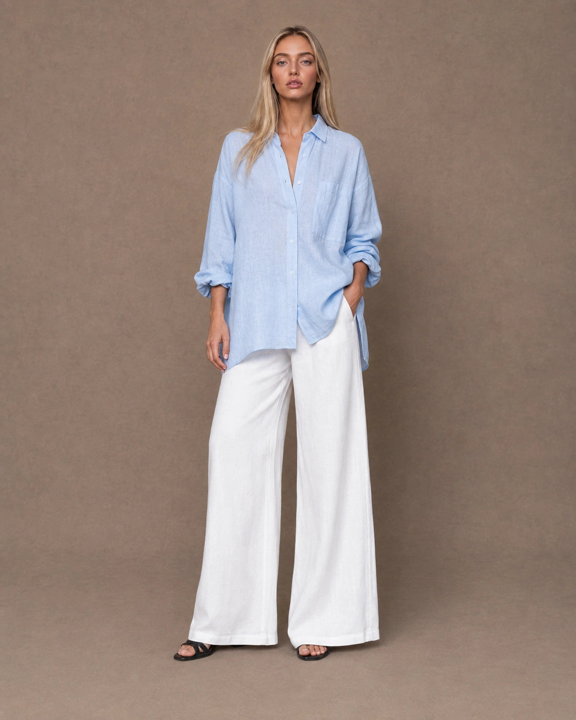 Volledige look van een vrouw in een relaxte lichtblauw linnen blouse, gecombineerd met een wijde broek.