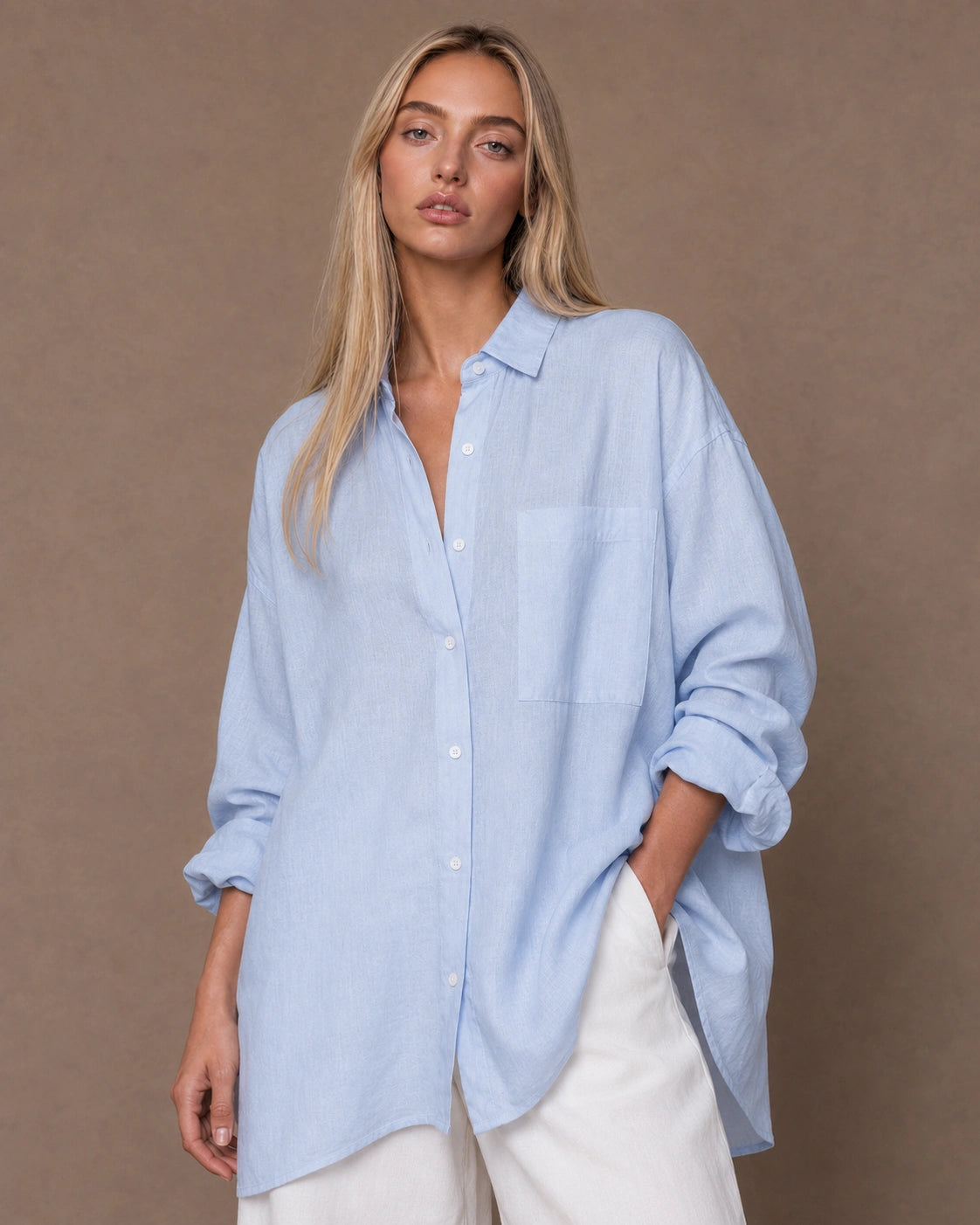 Vrouw draagt een relaxte lichtblauw linnen blouse met reverskraag en lange mouwen, vooraanzicht.