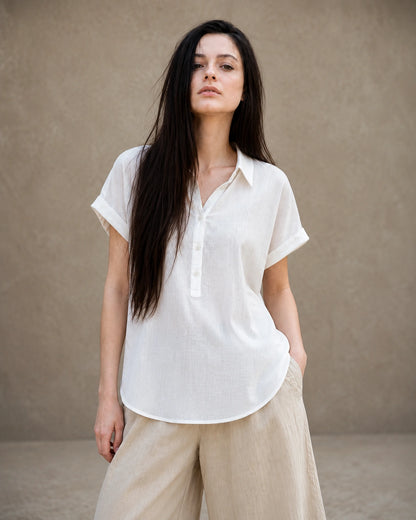 Vrouw draagt een wit linnen-lyocell instapblouse met reverskraag en korte mouwen, vooraanzicht.