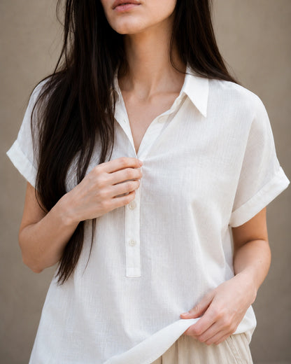 Close-up van de zachte, lichte stofstructuur van een wit linnen-lyocell blouse.