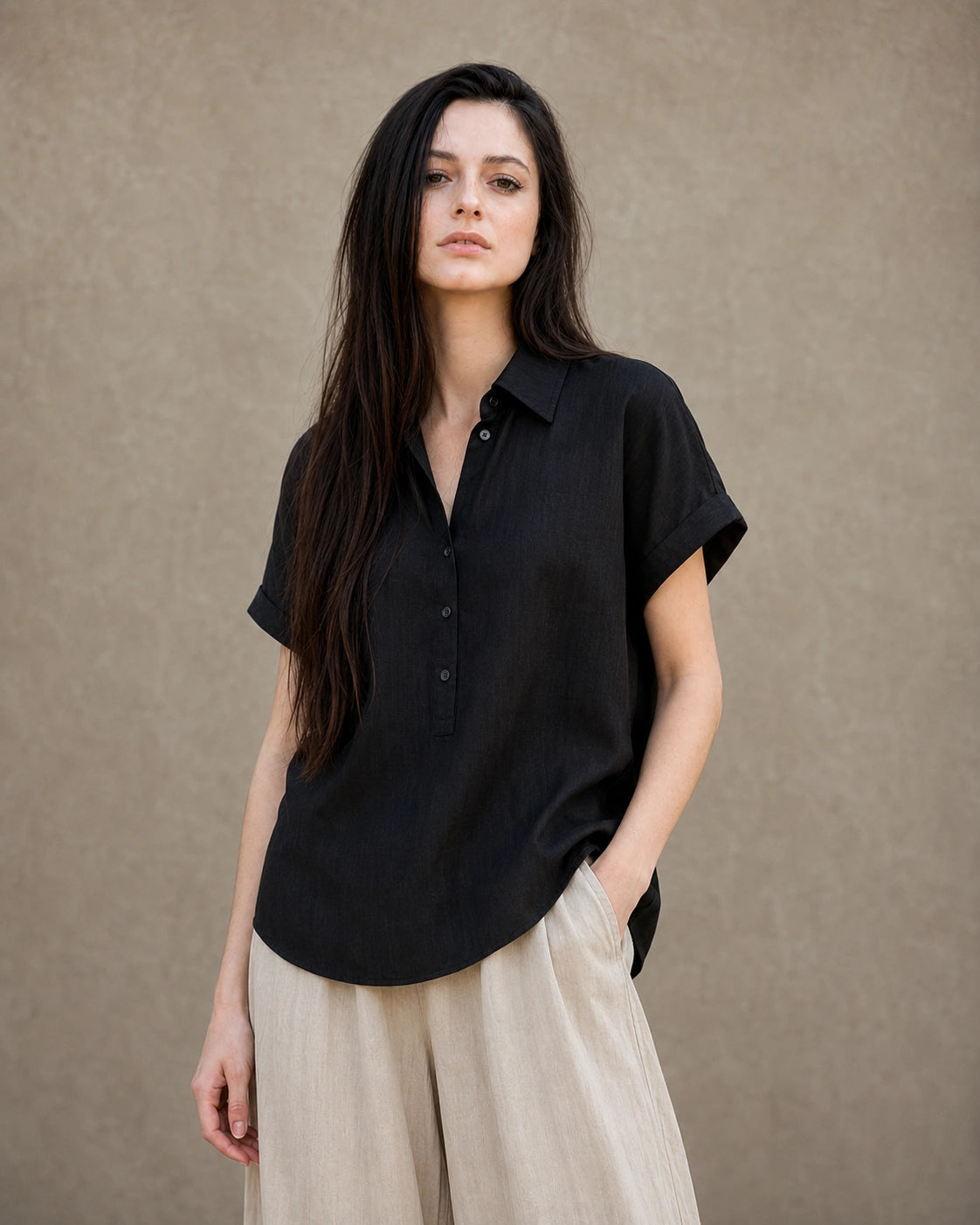 Vrouw draagt een zwart linnen-lyocell instapblouse met reverskraag en korte mouwen, vooraanzicht.