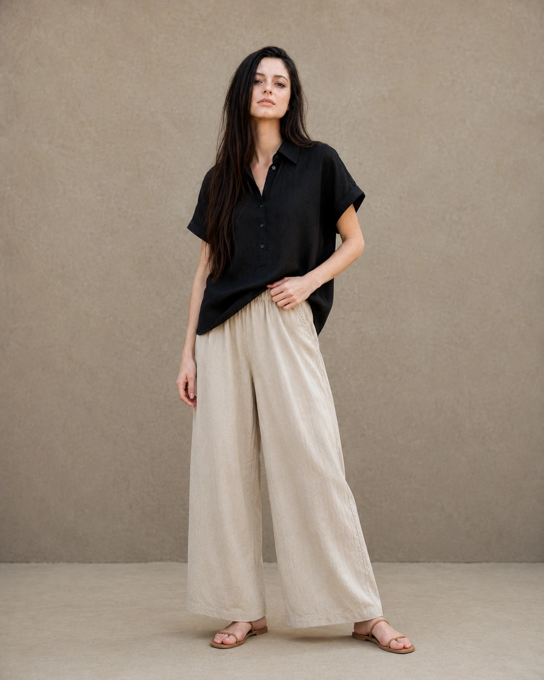 Volledige look van een vrouw in een zwart linnen-lyocell blouse, gecombineerd met een wijde linnen broek.