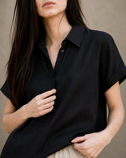 Close-up van de zachte, lichte stofstructuur van een zwart linnen-lyocell blouse.