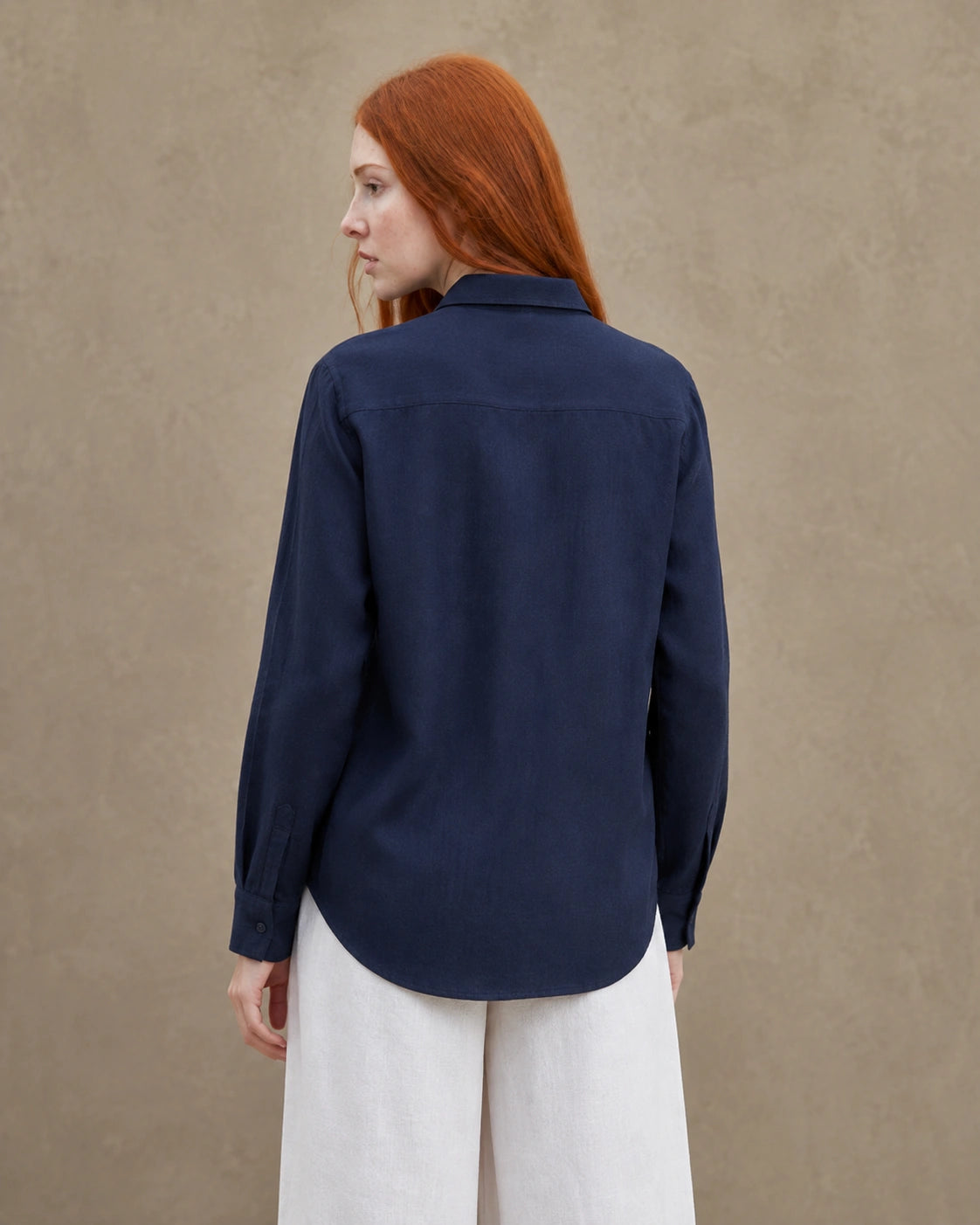 Achteraanzicht van een marineblauw linnen blouse met getailleerde kraag en lange mouwen.