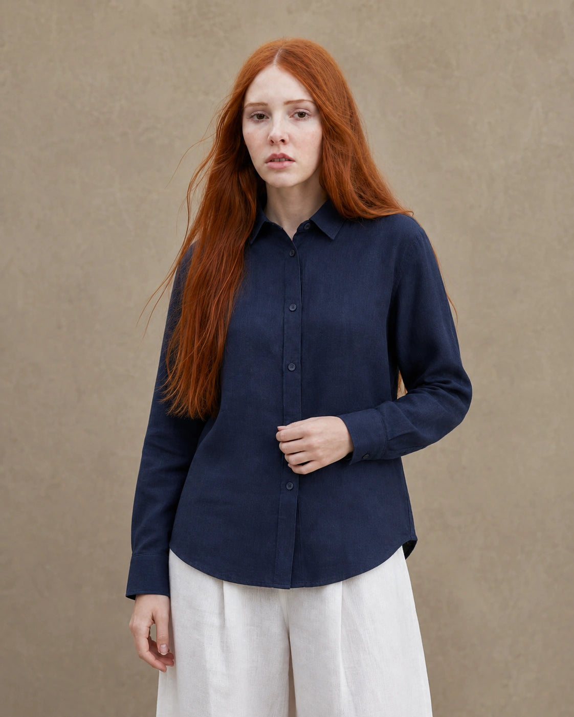 Vrouw draagt een marineblauw linnen blouse met getailleerde kraag en lange mouwen, vooraanzicht.