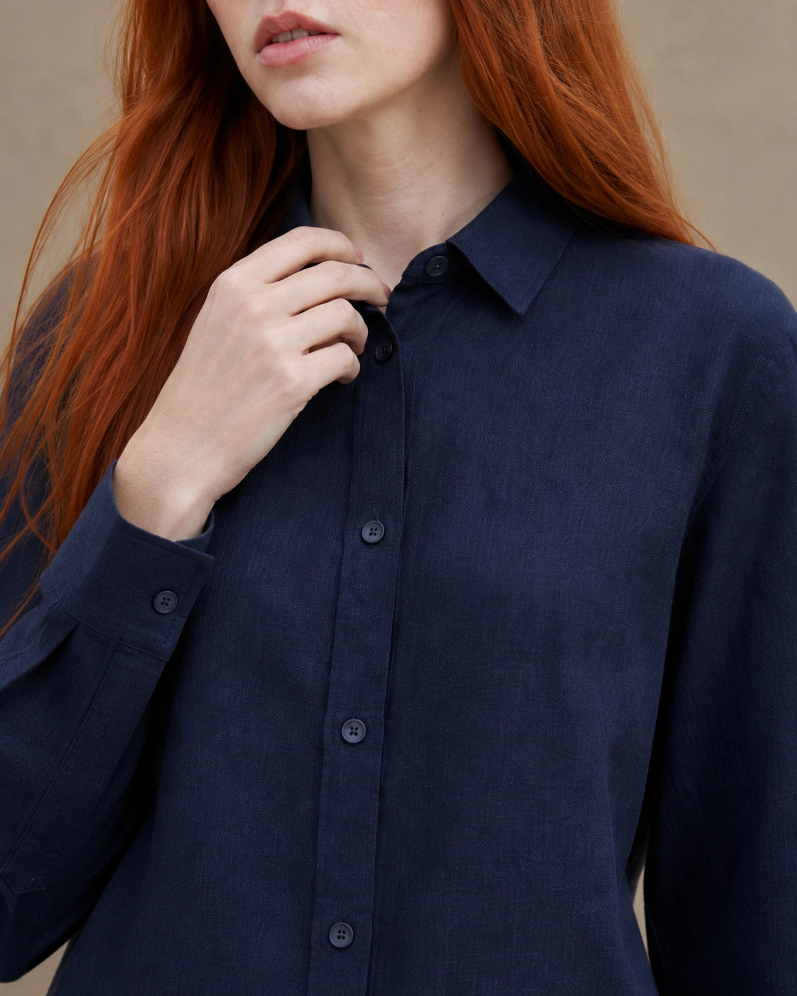 Close-up van de getailleerde kraag en knopenlijst van een marineblauw linnen blouse.