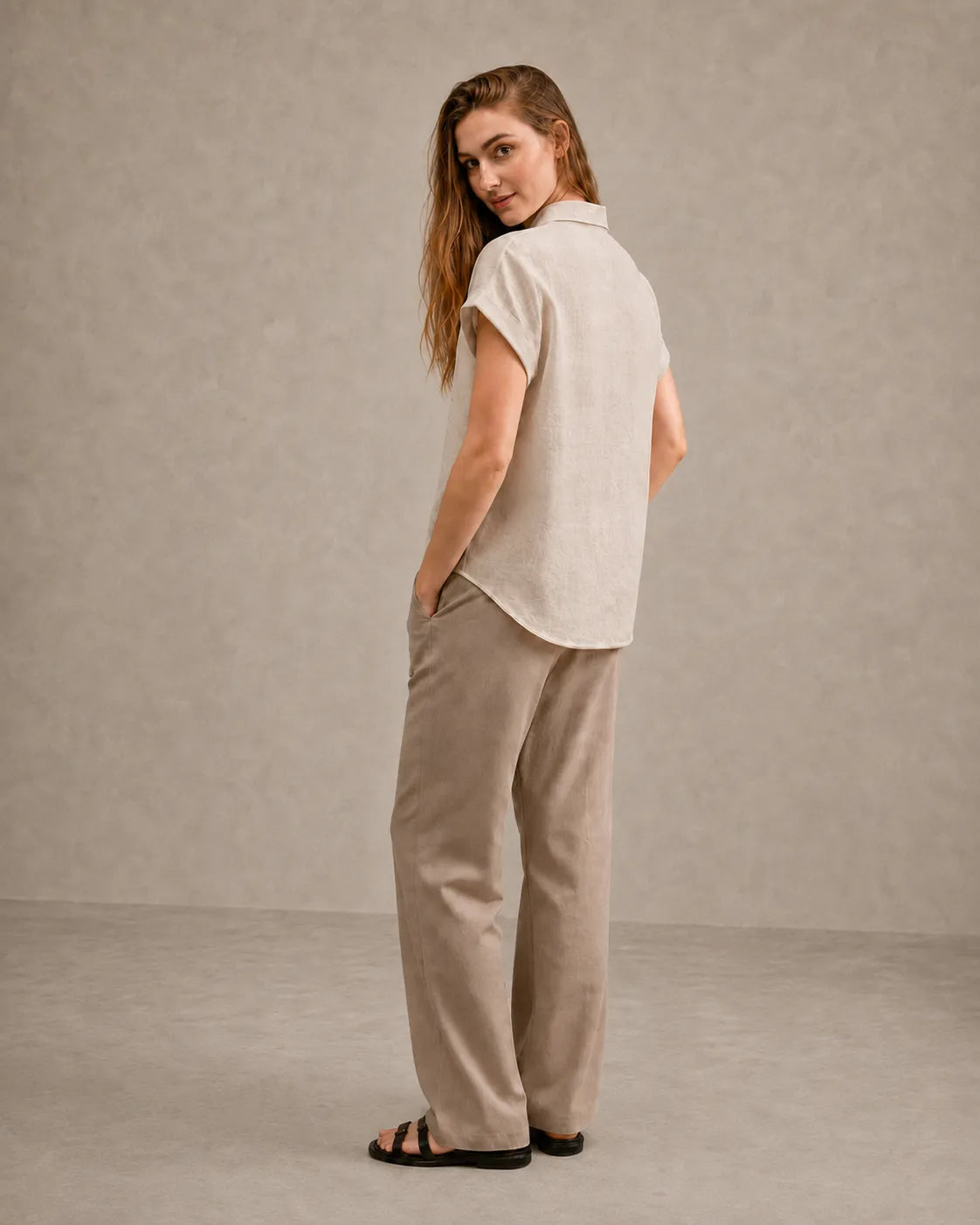 Three-quarter back view of a woman wearing a natural undyed linen shirt with a polo collar.