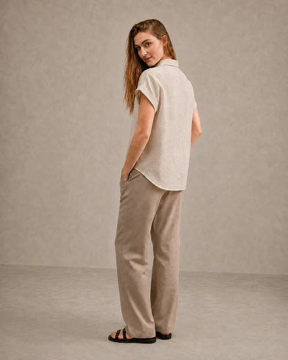 Three-quarter back view of a woman wearing a natural undyed linen shirt with a polo collar.