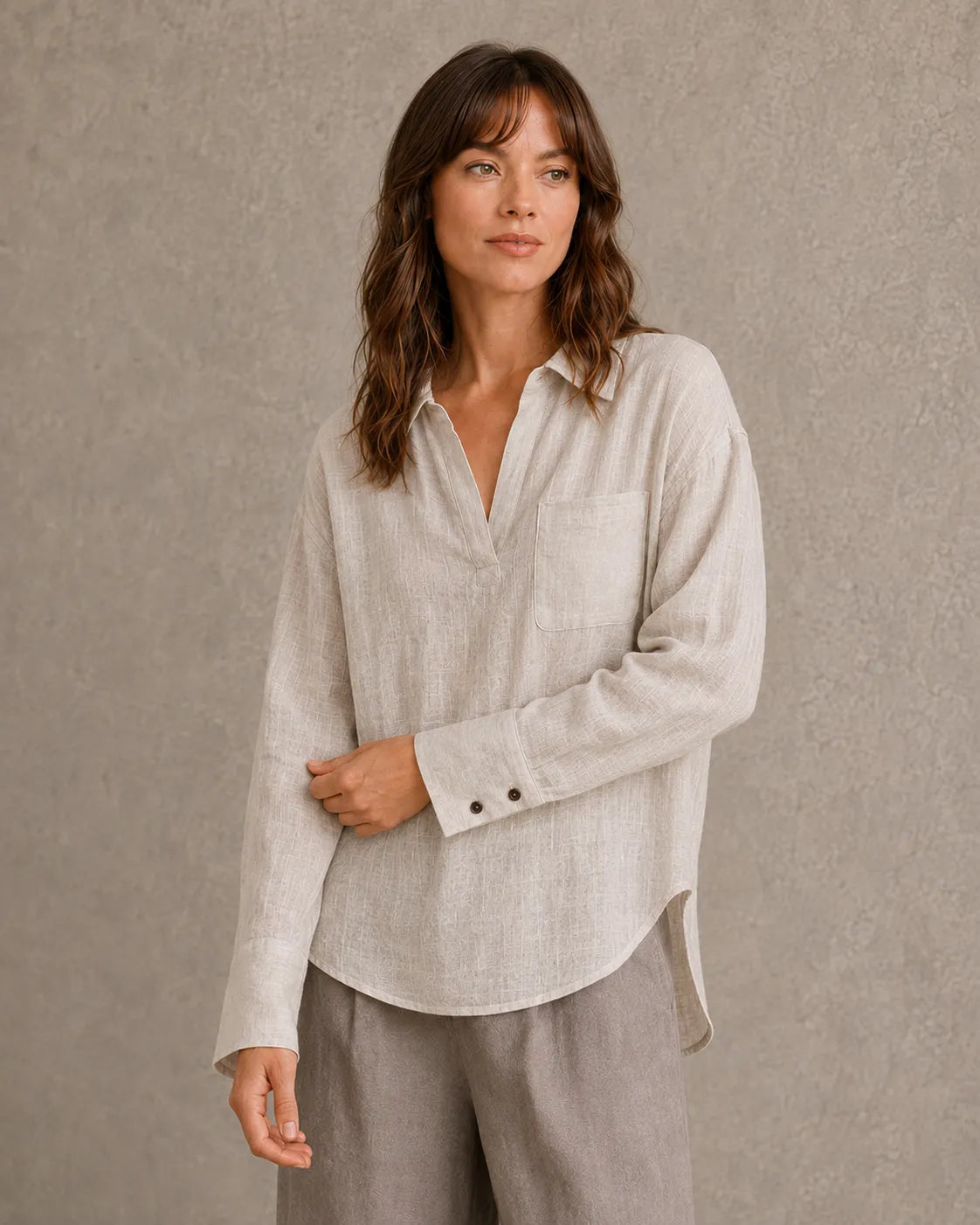 Vrouw draagt een naturel linnen blouse met V-hals reverskraag en lange mouwen, vooraanzicht.