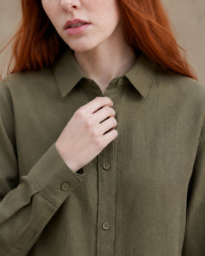 Close-up van de getailleerde kraag en knopenlijst van een olijfgroen linnen blouse.