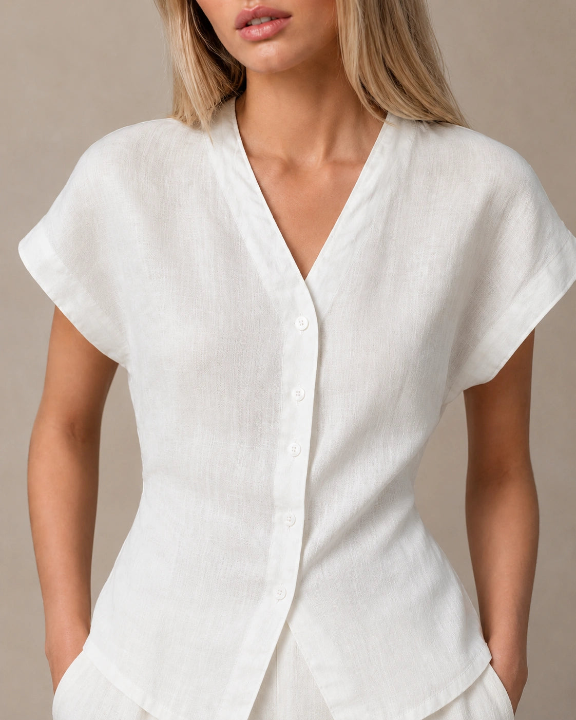 Close-up van de gedrapeerde, geplooide voorkant van een slank gesneden parelwit linnen blouse.