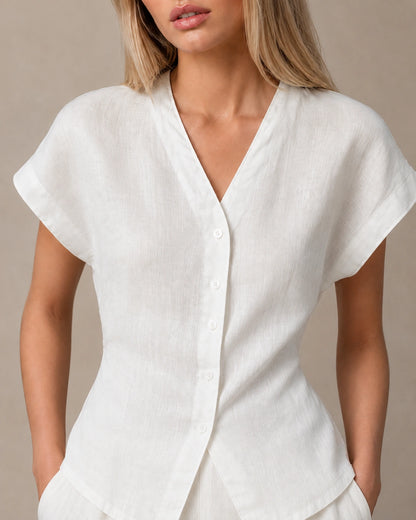Close-up van de gedrapeerde, geplooide voorkant van een slank gesneden parelwit linnen blouse.
