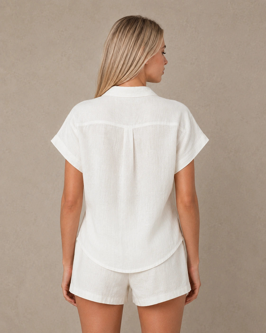 Achteraanzicht van een slank gesneden parelwit linnen blouse met korte mouwen.