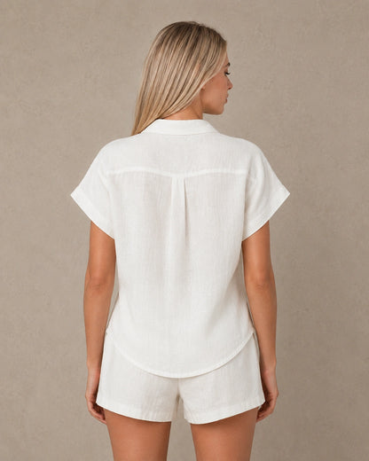 Achteraanzicht van een slank gesneden parelwit linnen blouse met korte mouwen.