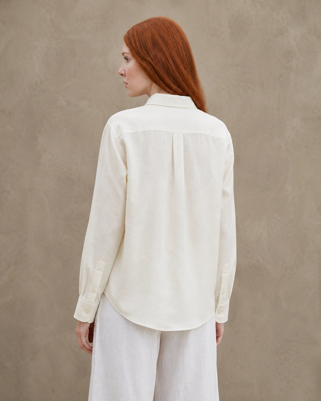 Achteraanzicht van een roomwit linnen blouse met getailleerde kraag en lange mouwen.